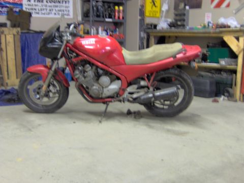 1993 Yamaha Seca II - A red Yamaha motorcycle sits in a cluttered garage, with various items stored on shelves behind it.