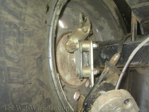 1990 Ford Bronco - Close-up view of a vehicle's rear brake assembly, showing the rotor, caliper bracket, and part of the tire.