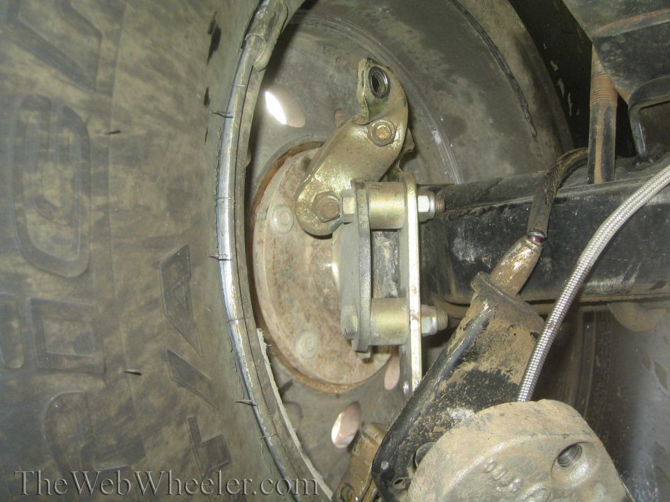 Drum brake backing plate and linkage behind a mud-terrain tire