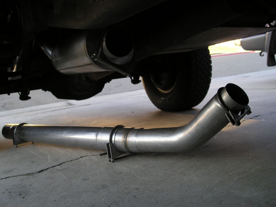 Exhaust pipe lying on the ground next to a vehicle's undercarriage
