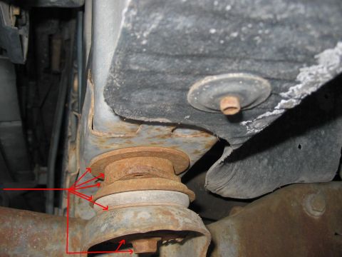 1991 Ford Bronco - Underside view of a vehicle's frame and suspension components, showing rust and wear on the metal parts.