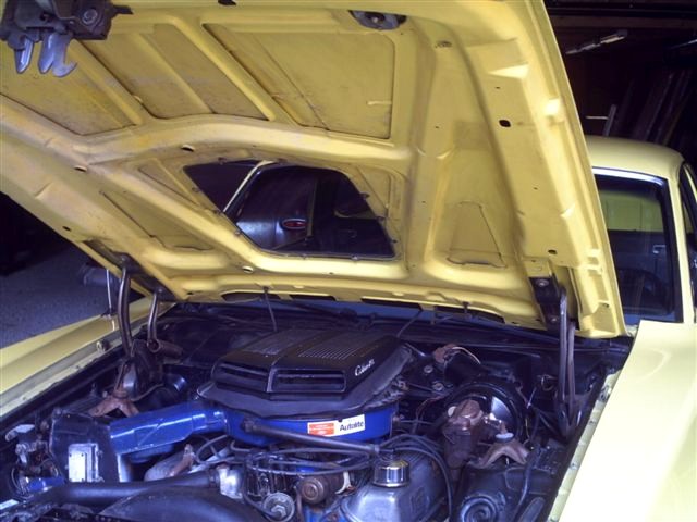 Yellow 1973 Ford Ranchero engine bay with hood open, showing the engine and air cleaner