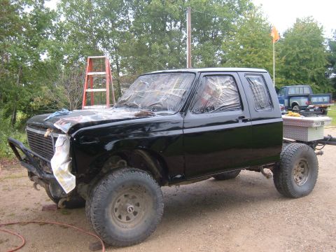 1985 Ford F-150 - A black pickup truck is parked outside with its windows covered, suggesting it is undergoing some form of work or repair.
