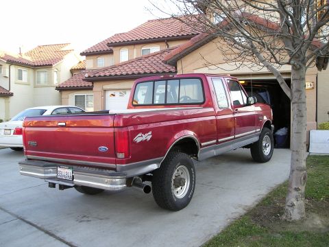 1997 Ford F-250 - This red 1997 Ford F-250 pickup truck is shown in a 3/4 rear view, parked in a driveway.