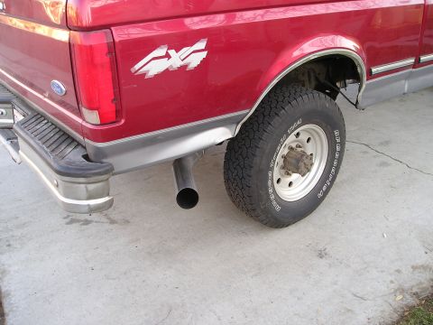 1997 Ford F-250 - Rear view of a red 1997 Ford F-250 pickup truck, showing the 4x4 decal and exhaust.