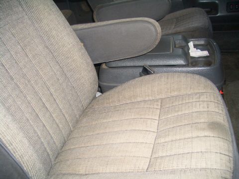 1988 Ford Bronco - Close-up of the interior showing the fabric seats and the center console area with a cup holder.