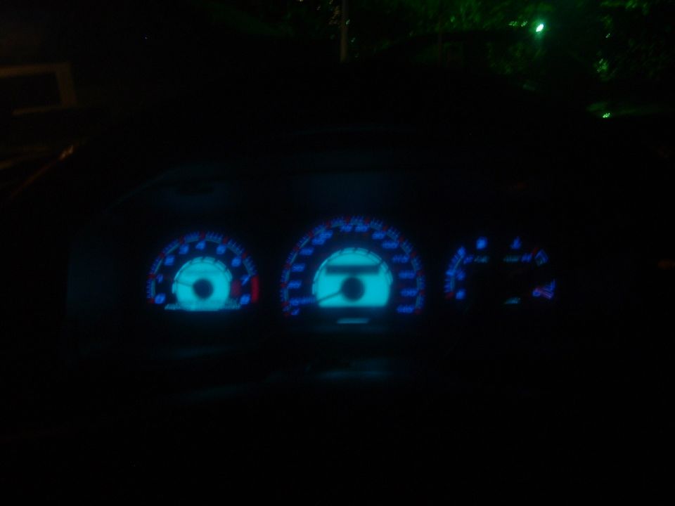 Dashboard gauges with blue illumination, viewed at night