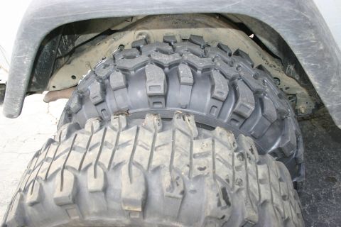 2003 Jeep TJ - Close-up view of two off-road tires, one stacked on top of the other, under a vehicle's fender.