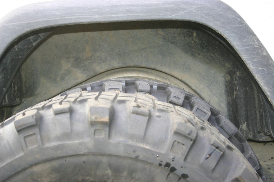 Close-up of a tire and wheel well, showing tread pattern and fender liner