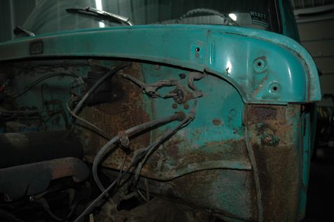 1963 Ford F-250 - The engine bay of a vintage truck shows significant rust and exposed wiring, hinting at its age and condition.