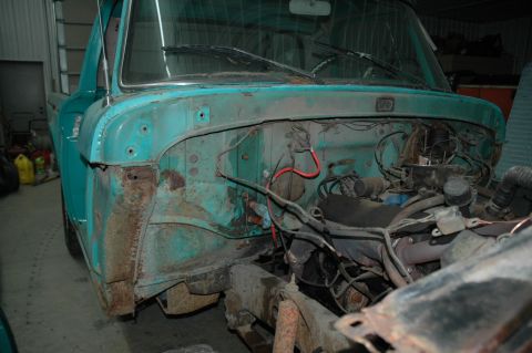 1963 Ford F-250 - The engine bay of a teal Ford F-series truck shows significant rust and disassembled parts.