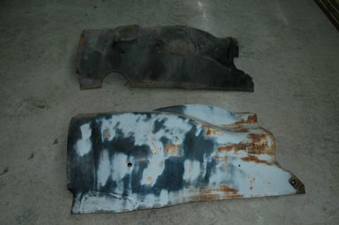 1963 Ford F-250 - Two old, rusty truck fender sections are laid out on a concrete floor.