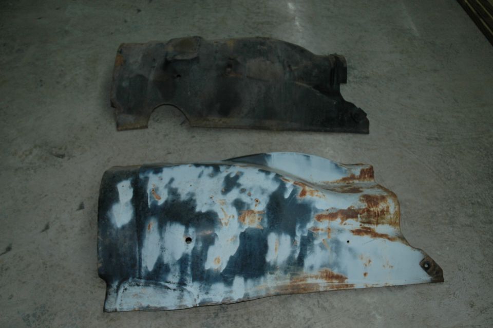 Two rusty truck fender sections, one dark and one with primer patches