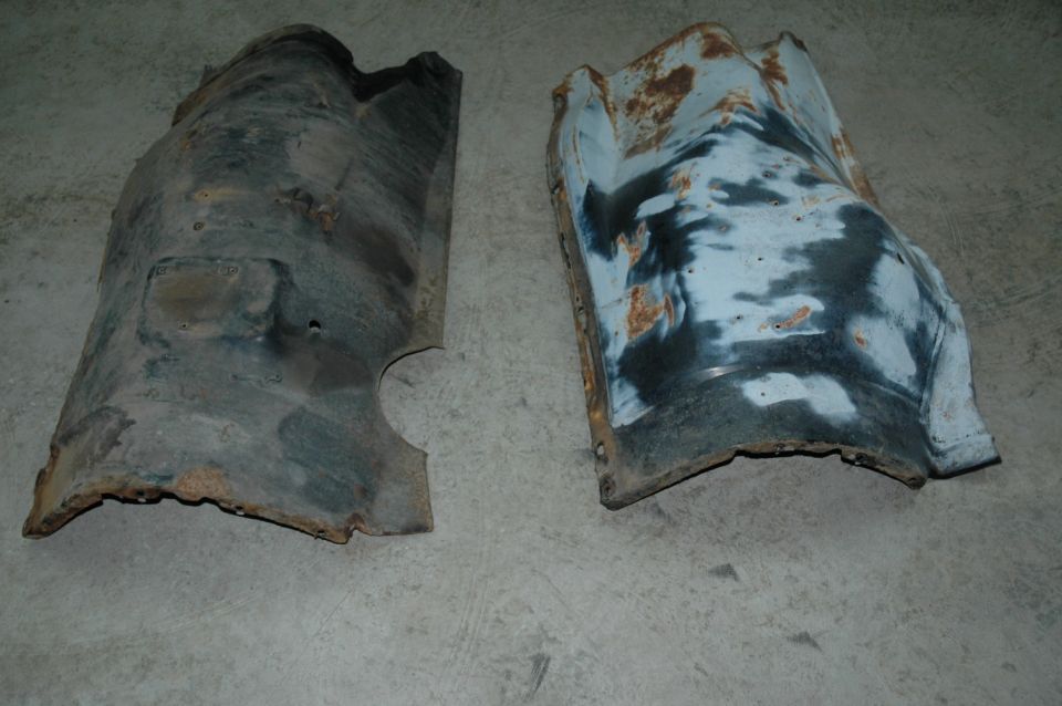 Two rusty, curved metal fender liners on a concrete floor