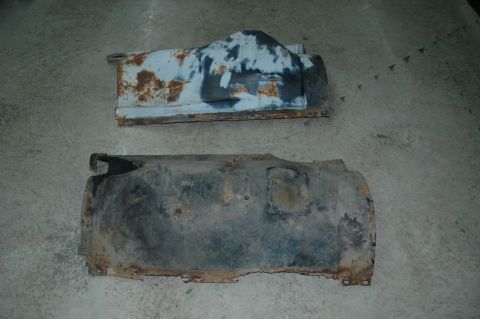 1963 Ford F-250 - Two rusty truck fender liners are shown on a concrete floor, likely parts from a disassembled vehicle.