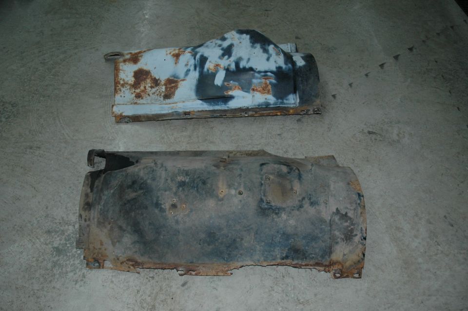 Two rusty truck fender liners on a concrete floor