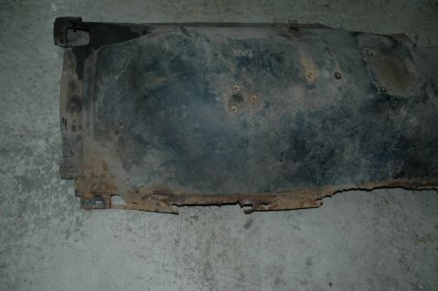 1963 Ford F-250 - A heavily rusted fender liner, possibly from a truck, lies on a concrete surface.