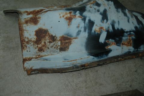 1963 Ford F-250 - A heavily rusted metal panel, likely a vehicle part, displays primer and undercoating with extensive corrosion.