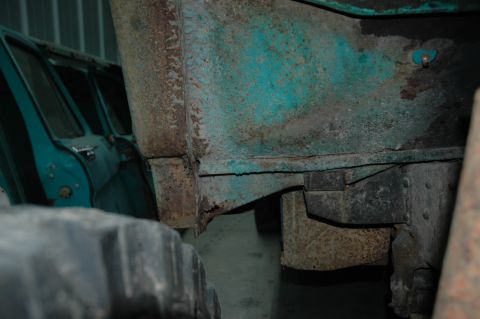 1963 Ford F-250 - Close-up of a heavily rusted 1963 Ford F-250 frame and tire, with another vehicle in the background.