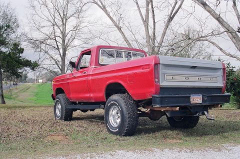 1979 Ford F-150 - A red pickup truck is parked outdoors on a cloudy day, viewed from the rear-three-quarter angle.