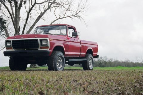 1979 Ford F-150 - A red 1979 Ford F-150 pickup truck is shown from a three-quarter front angle in an outdoor setting.