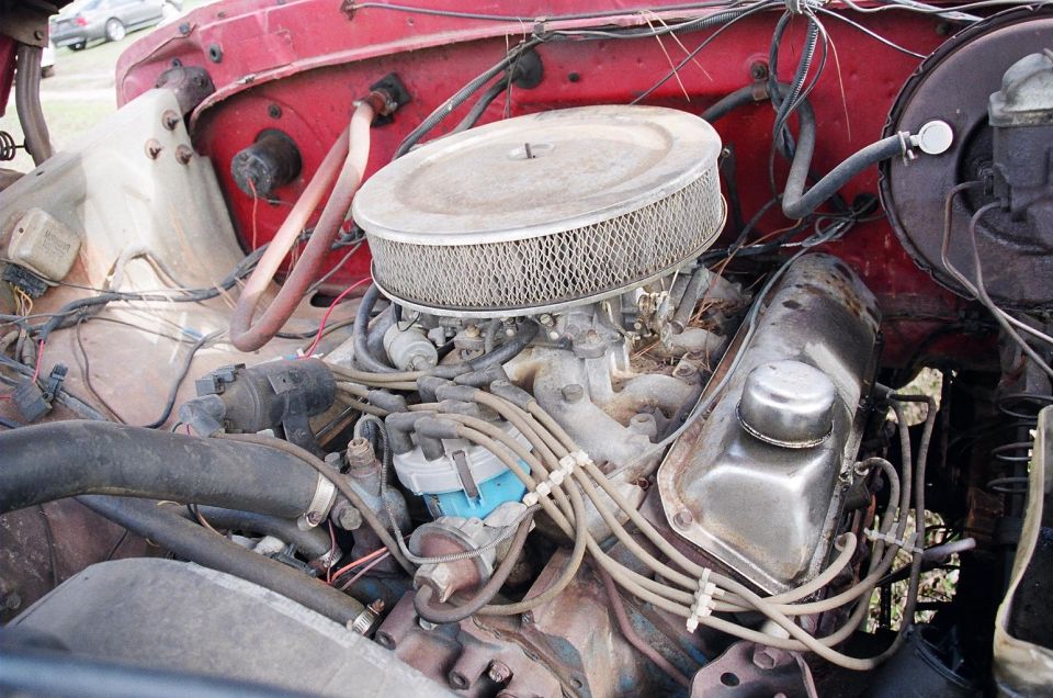 Engine bay with a carburetor and air filter. Some hoses and wiring are visible