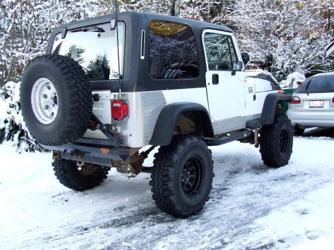 1991 Jeep Wrangler - Rear view of a 1991 Jeep Wrangler parked in the snow with a spare tire on the back.