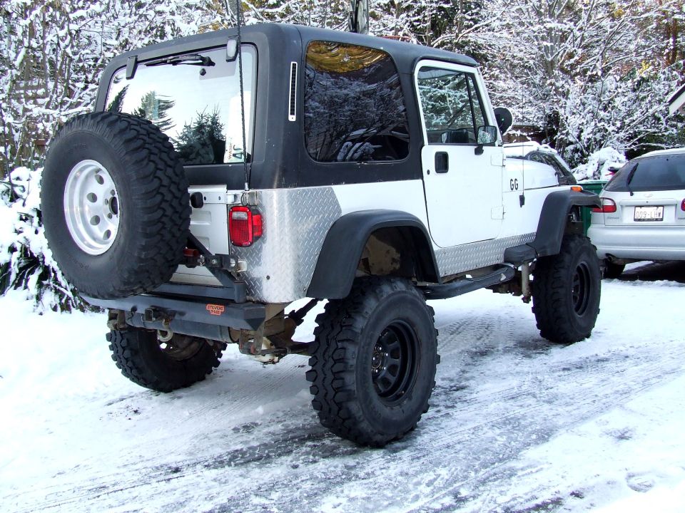 1991 Jeep Wrangler, white with black top, in snow, spare tire mounted on rear carrier