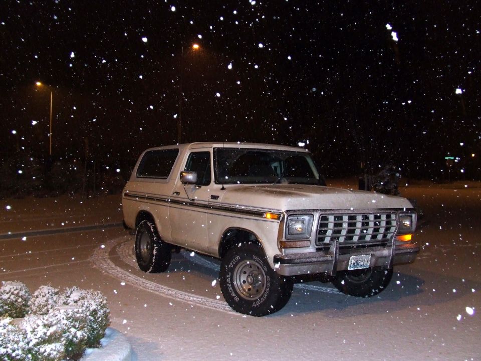 White 1978 Ford Bronco with chrome grille and side trim parked in snow