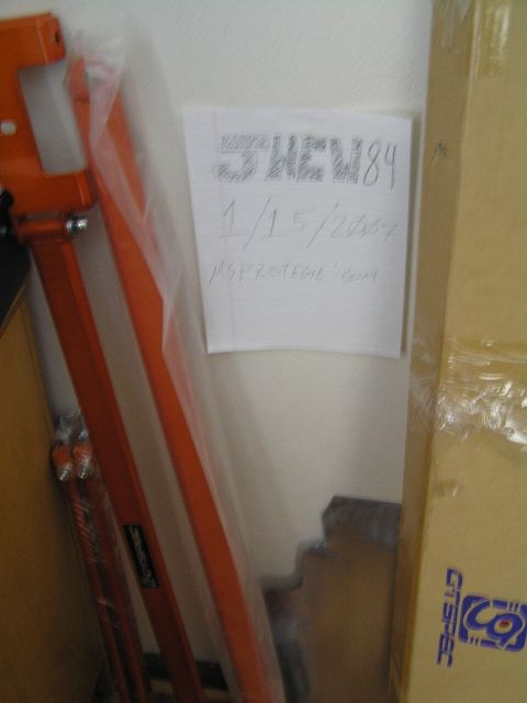 2003 Mazda Protege - A handwritten note is taped to a wall in a garage, with various items stored around it.
