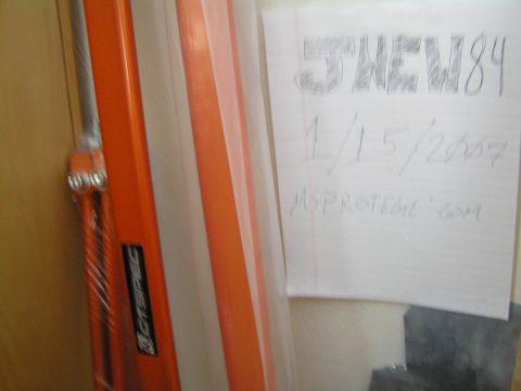 2003 Mazda Protege - A handwritten note with vehicle information is attached to an orange and white striped object.