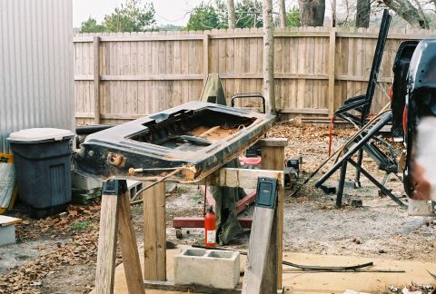 1978 Ford Bronco - A disassembled car door is propped up on sawhorses in a yard, awaiting restoration.