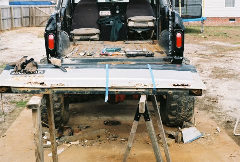 1978 Ford Bronco - The rear of a 1978 Ford Bronco is shown with its tailgate removed, revealing tools and a worn interior.