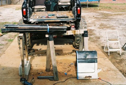 1978 Ford Bronco - Rear view of a 1978 Ford Bronco undergoing work, with parts laid out around it.