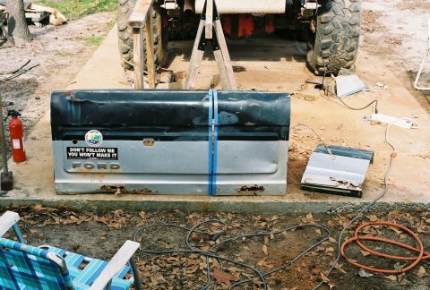1978 Ford Bronco - A detached Ford tailgate rests on a concrete pad, showing signs of rust and wear.
