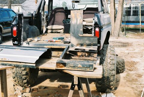 1978 Ford Bronco - The rear of a 1978 Ford Bronco is shown disassembled, resting on sawhorses with large off-road tires.
