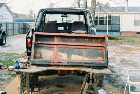 1978 Ford Bronco - The tailgate of an old SUV is removed and resting on sawhorses, with tools nearby for repair nearby.