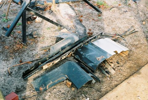 1978 Ford Bronco - Debris from a vehicle, including bent metal and body panels, lies scattered on the ground.