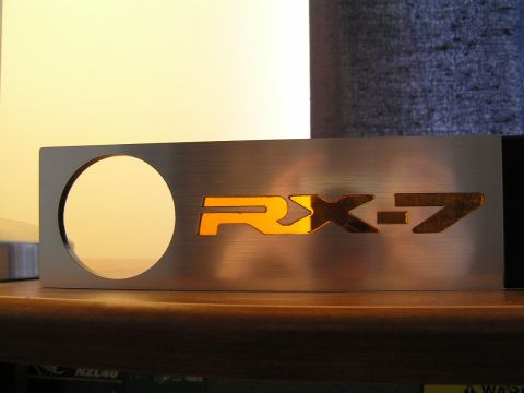 1993 Mazda RX-7 - This brushed metal panel features the illuminated RX-7 emblem, likely an aftermarket part for a Mazda RX-7.