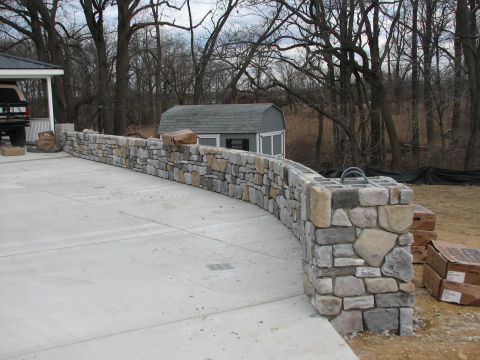 1992 Ford Bronco - A stone wall curves around a concrete driveway, with a shed visible in the background.