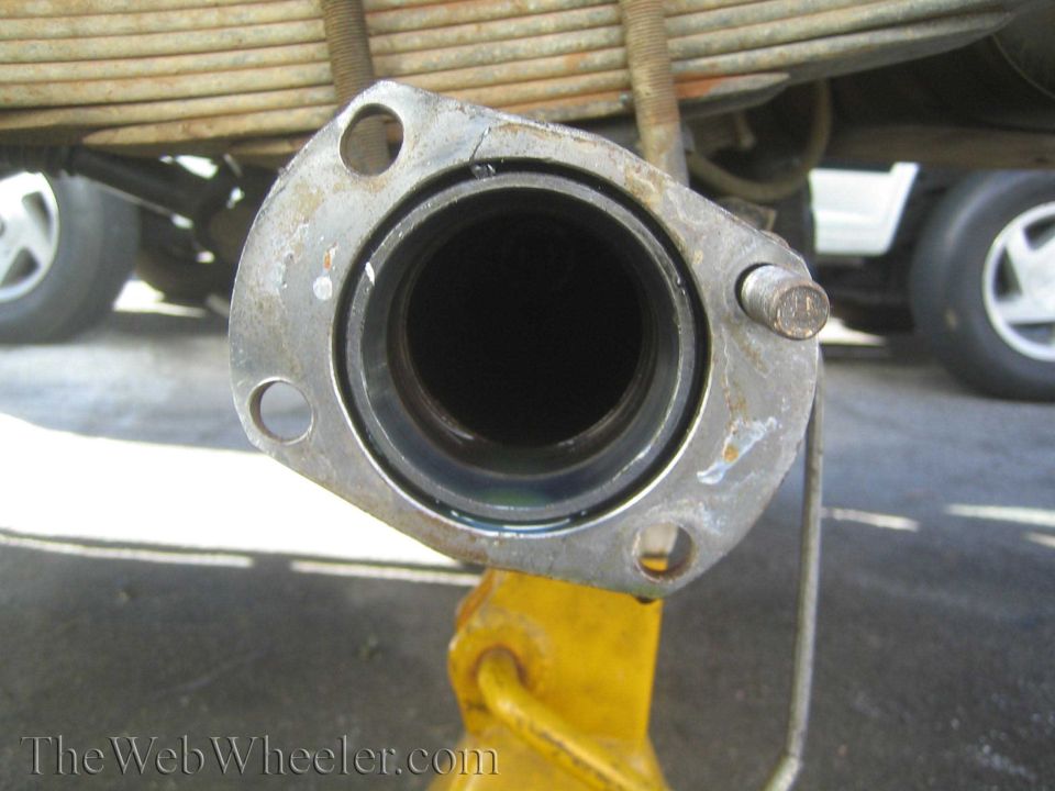 End view of an axle tube flange bore with leaf spring above on a jack