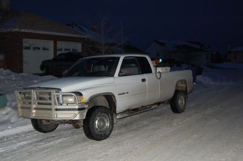 1996 Dodge 2500 - A white 1996 Dodge 2500 pickup truck is parked on a snow-covered street in front of a garage at night.