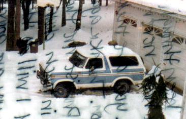 1991 Ford Bronco - 1980-1986 Ford Bronco covered in snow, parked outside a residential garage.