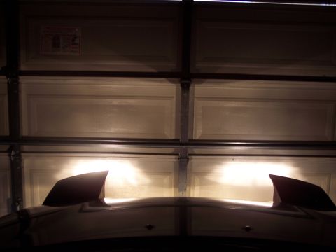 1995 Ford Probe - The headlights of a car are illuminated inside a garage, with a closed garage door in the background.