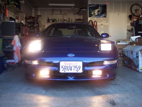 1995 Ford Probe - A blue Ford Probe with its distinctive pop-up headlights illuminated is parked inside a garage.