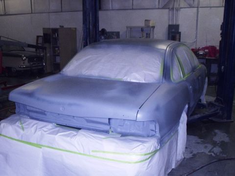 1996 Ford Crown Victoria - A car is masked and prepped for a refinish process in a workshop, with another vehicle in the background.