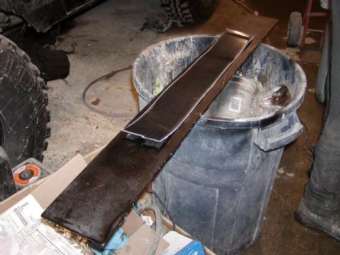 1979 Ford F-150 - A metal trim piece is placed on top of a large trash can in a workshop setting.