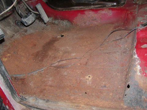 1979 Ford F-150 - The interior floor pan shows significant rust and holes, with visible pedals.