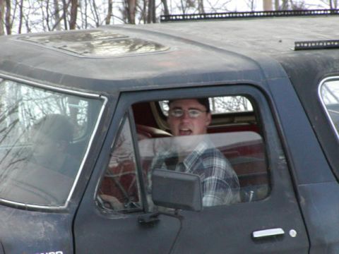 1979 Ford F-150 - A person looks out from the driver's seat of a dark-colored vehicle with a sunroof and light bar.