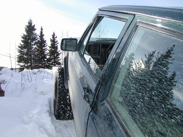 Side view of dark green SUV with large tires in snow